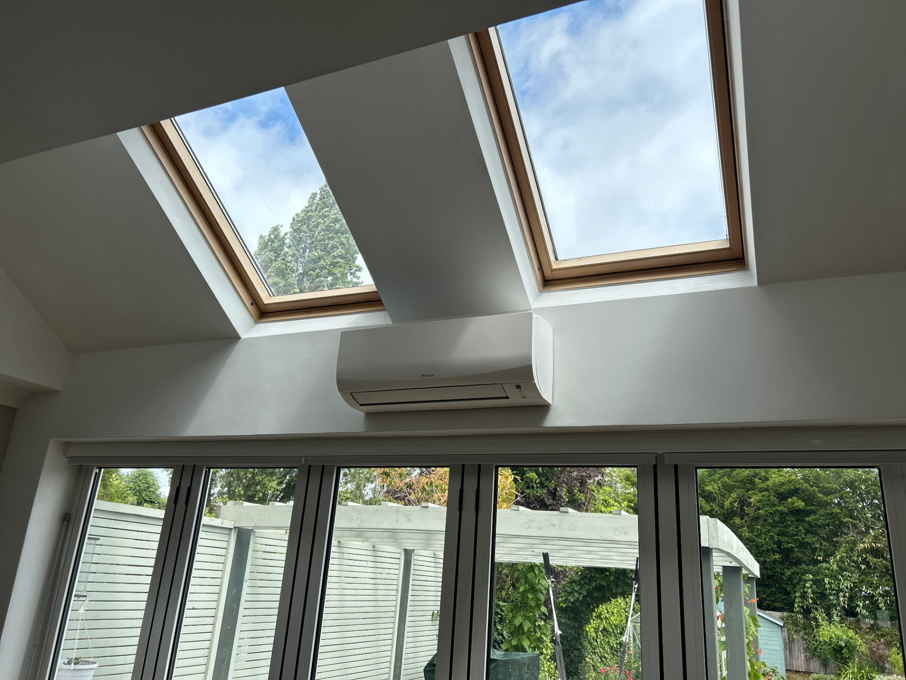 Indoor air conditioning unit installed below two rooflights in a bright Richmond loft conversion