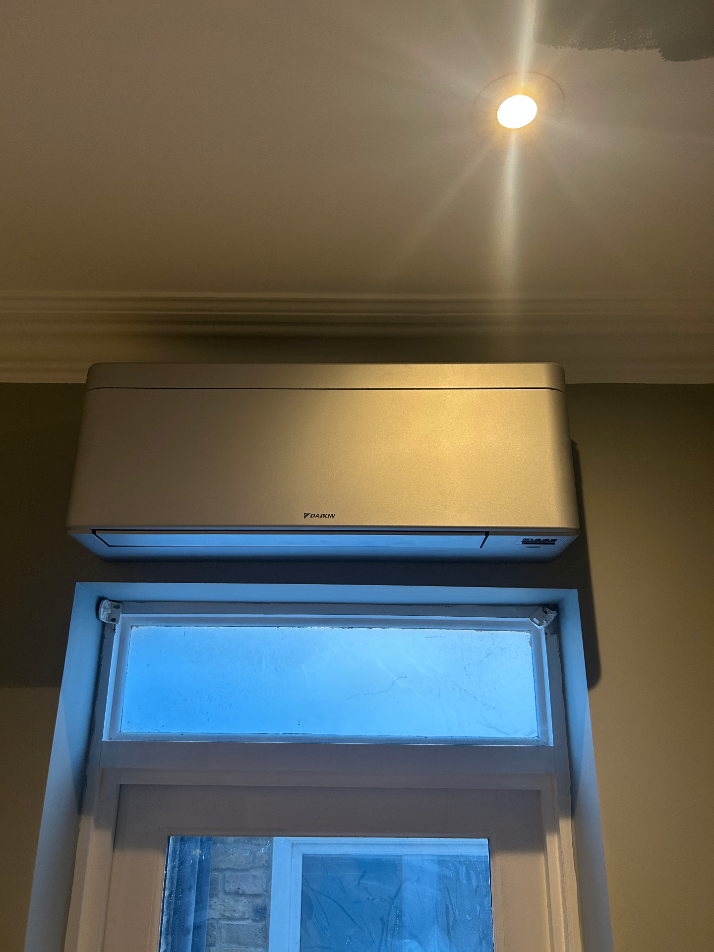Silver wall-mounted air conditioning unit installed above a doorway in Fulham