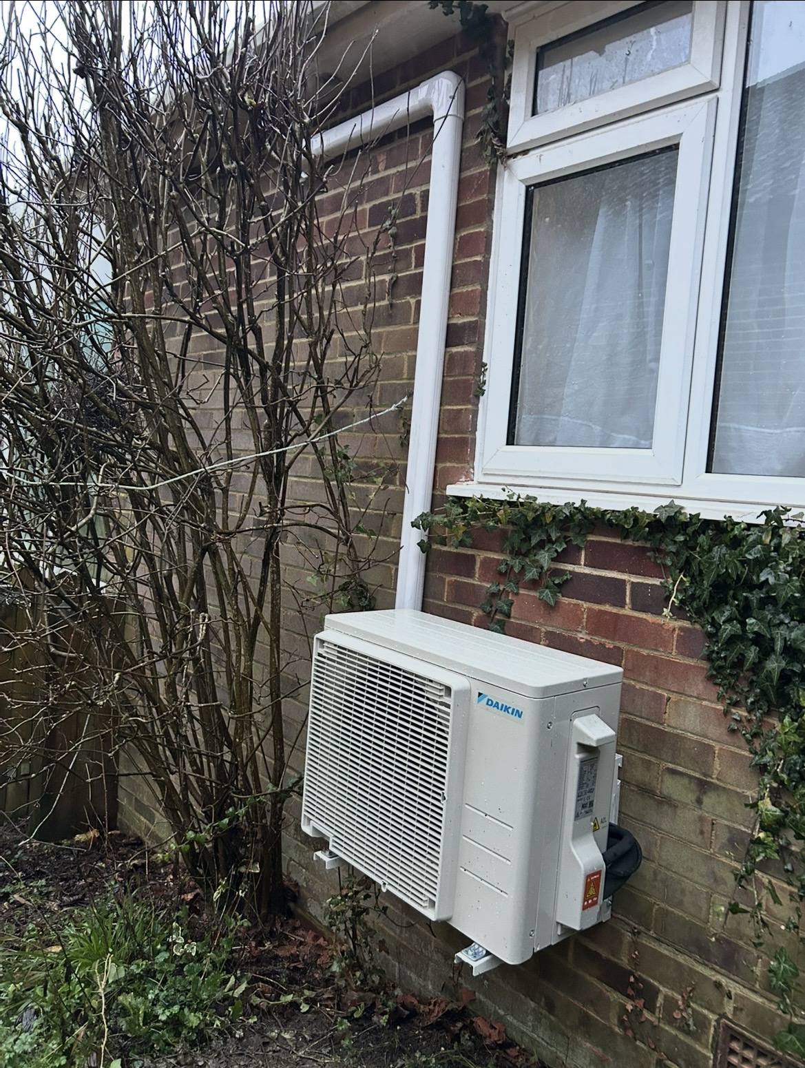Daikin outdoor condenser mounted beside a brick house in Battersea with neat pipework