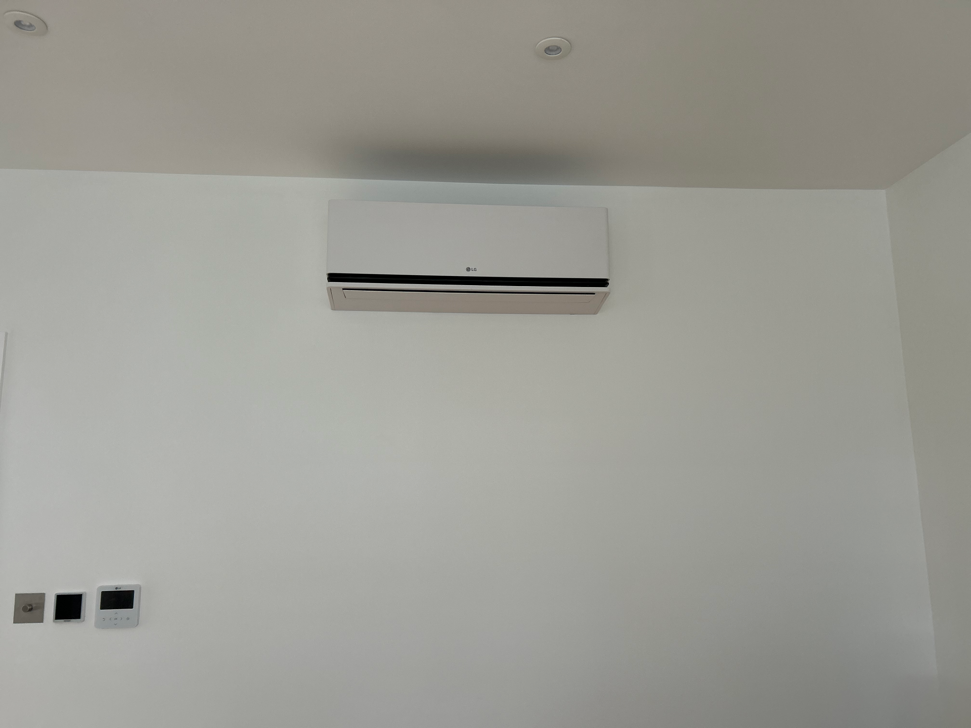 Minimal white LG wall-mounted air conditioning unit fitted high on a Richmond bedroom wall