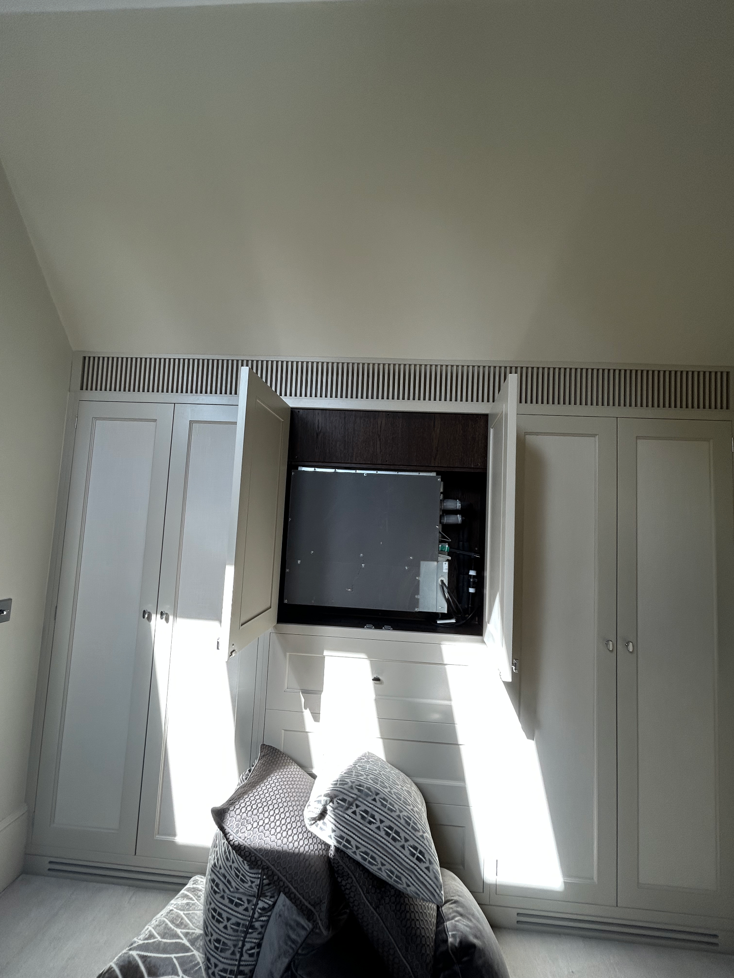 Concealed ducted air conditioning unit hidden inside bespoke joinery in a Wandsworth bedroom