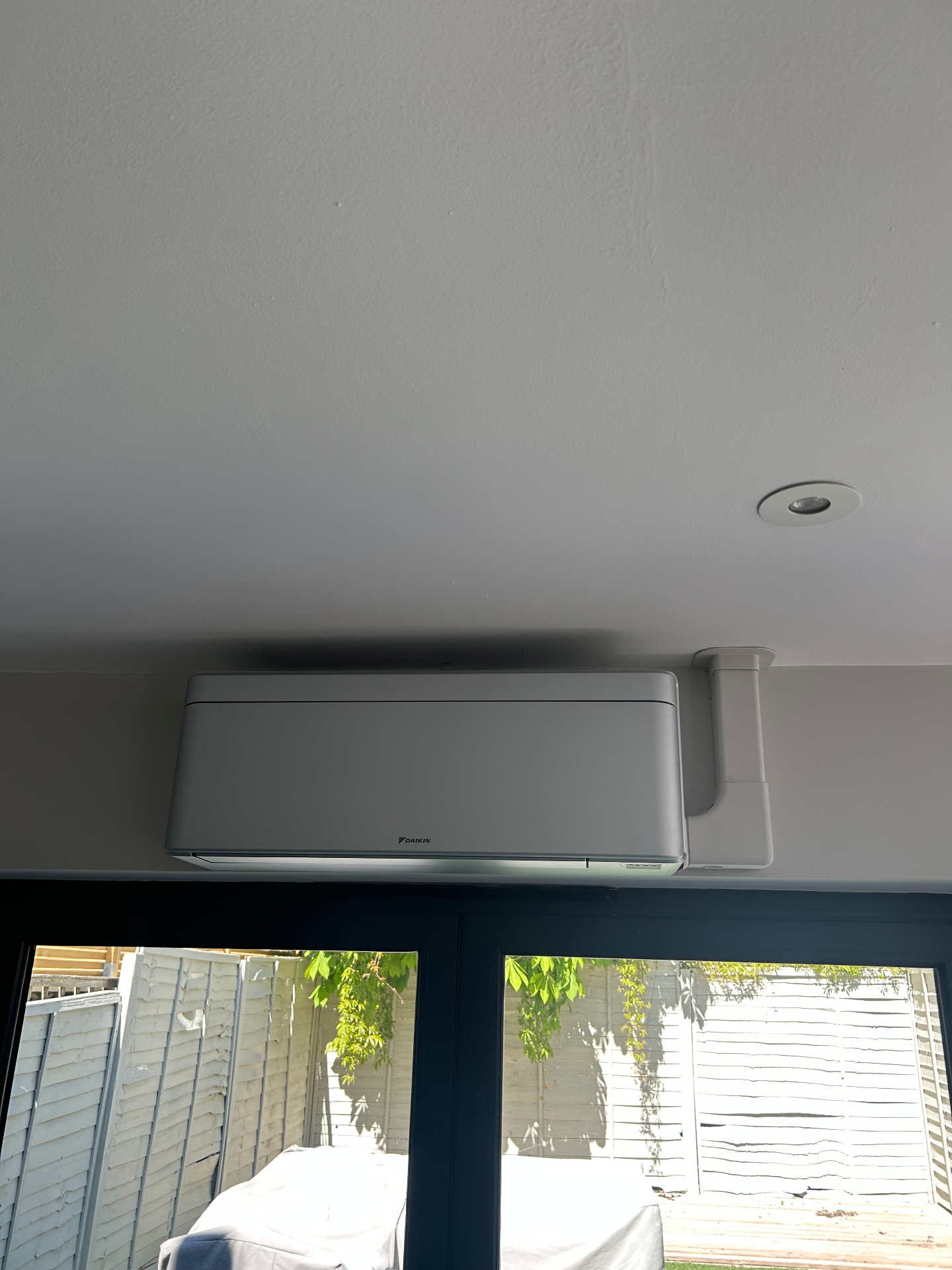 Silver Daikin wall-mounted air conditioning unit above black-framed doors in a Fulham home